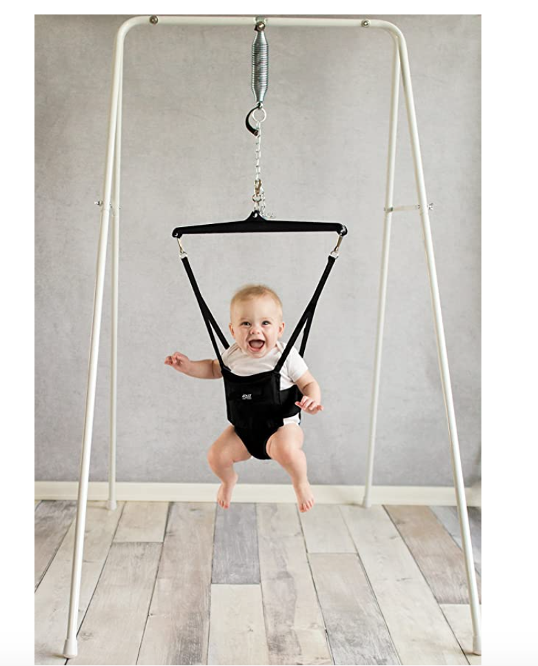 Baby in mid-jolly jump, in harness attached to triangular thingie.