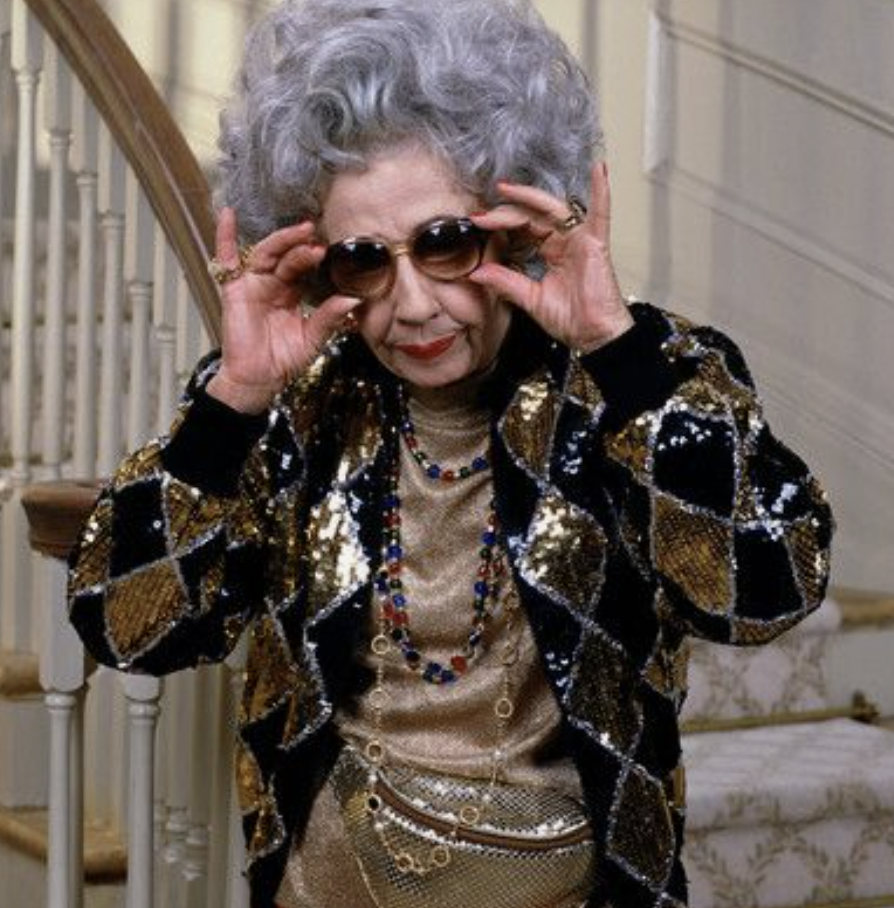 Yetta in black and gold sequined jacket, jewelry and sequined waist pack.